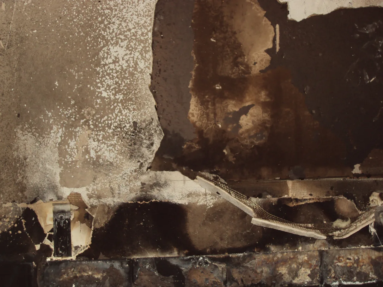 Fire-damaged wall with exposed charred material, representative assessment context